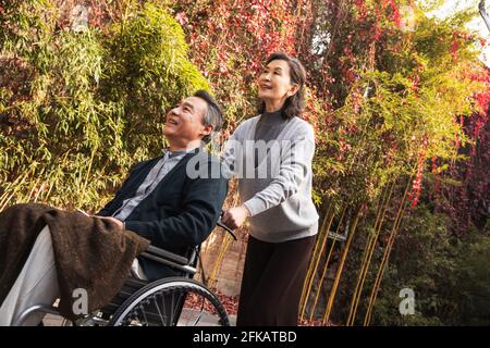 Sua moglie di donne anziane che spingono una sedia a rotelle Foto Stock
