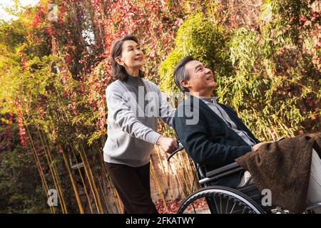 Sua moglie di donne anziane che spingono una sedia a rotelle Foto Stock