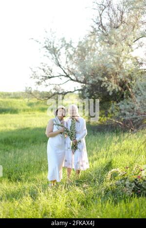 Ritratto di granata con figlia che cammina all'aperto, indossando abiti bianchi. Foto Stock