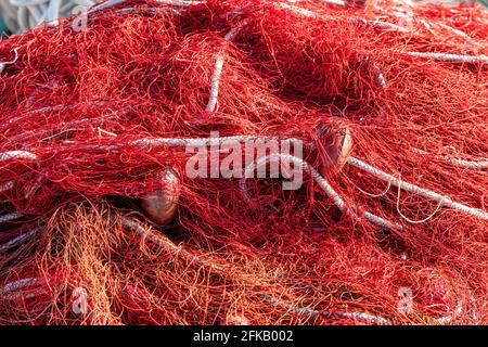 Reti da pesca rosse con galleggianti e corde. Foto di natura morta, immagine perfetta per l'acquacoltura, la pesca intensiva e la tutela dell'ambiente. Foto Stock