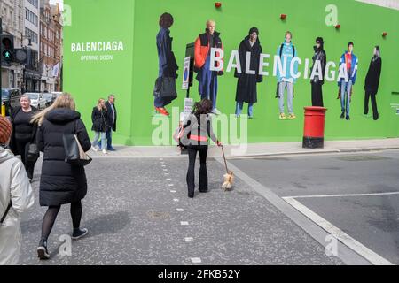 Gli acquirenti attraversano la strada verso l'imbarco temporaneo per Balenciaga, uno spazio al dettaglio che sta per aprirsi a breve su Bond Street, il 27 aprile 2021, a Londra, Inghilterra. Balenciaga è una casa di moda fondata nel 1917 dallo stilista spagnolo Cristóbal Balenciaga a San Sebastián, Spagna. Foto Stock