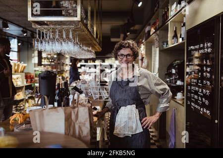 Ritratto di donna sorridente proprietario con mano sull'anca a. negozio di gastronomia Foto Stock