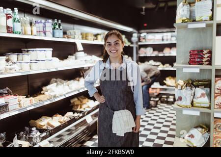 Ritratto di donna sorridente con mano sull'anca negozio di gastronomia Foto Stock