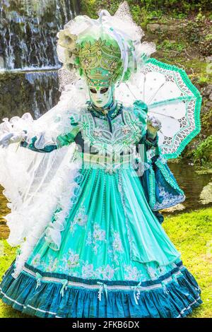 Costume veneziano verde brillante che porta un ombrello Foto Stock