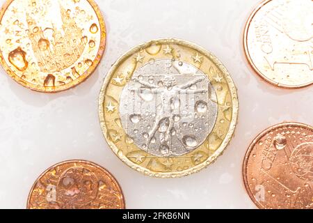 Monete in euro, euro e centesimi di euro su sfondo bianco. Monete con gocce d'acqua. Foto Stock