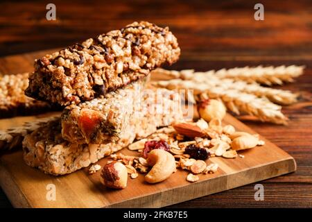 Mazzetto di barrette energetiche a base di muesli senza glutine con frutta secca e vari tipi di noci, fondo in legno. Cibo vegan sano super, diversa dieta fitness sn Foto Stock