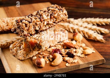 Mazzetto di barrette energetiche a base di muesli senza glutine con frutta secca e vari tipi di noci, fondo in legno. Cibo vegan sano super, diversa dieta fitness sn Foto Stock