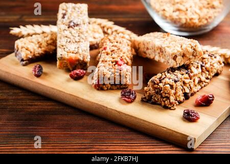 Mazzetto di barrette energetiche a base di muesli senza glutine con frutta secca e vari tipi di noci, fondo in legno. Cibo vegan sano super, diversa dieta fitness sn Foto Stock