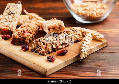 Mazzetto di barrette energetiche a base di muesli senza glutine con frutta secca e vari tipi di noci, fondo in legno. Cibo vegan sano super, diversa dieta fitness sn Foto Stock