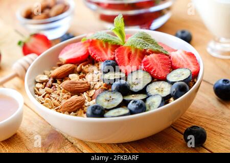 Possibilità di servire una ciotola alla granola con un mix di frutta secca, cereali, frutta e frutti di bosco, yogurt greco. Sana colazione vegetariana, fragola biologica, blueberr Foto Stock