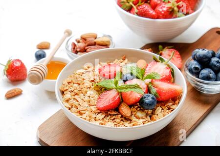 Possibilità di servire una ciotola alla granola con un mix di frutta secca, cereali, frutta e frutti di bosco, yogurt greco. Sana colazione vegetariana, fragola biologica, blueberr Foto Stock