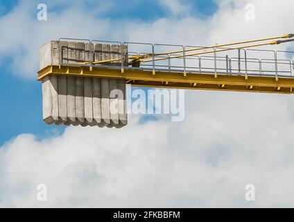 Bielorussia, Minsk - 28 maggio 2020: Un contrappeso di blocchi di cemento sulla coda di una gru a torre contro un cielo blu con le nuvole. Primo piano. Foto Stock