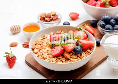 Possibilità di servire una ciotola alla granola con un mix di frutta secca, cereali, frutta e frutti di bosco, yogurt greco. Sana colazione vegetariana, fragola biologica, blueberr Foto Stock