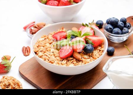 Possibilità di servire una ciotola alla granola con un mix di frutta secca, cereali, frutta e frutti di bosco, yogurt greco. Sana colazione vegetariana, fragola biologica, blueberr Foto Stock