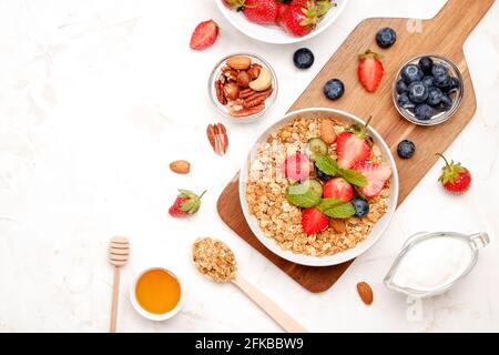 Possibilità di servire una ciotola alla granola con un mix di frutta secca, cereali, frutta e frutti di bosco, yogurt greco. Sana colazione vegetariana, fragola biologica, blueberr Foto Stock