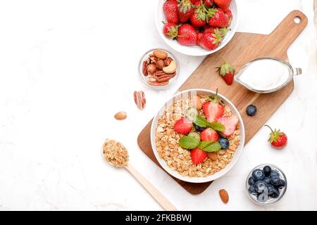 Possibilità di servire una ciotola alla granola con un mix di frutta secca, cereali, frutta e frutti di bosco, yogurt greco. Sana colazione vegetariana, fragola biologica, blueberr Foto Stock