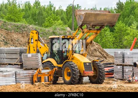 Bielorussia, Minsk - 28 maggio 2020: Bulldozer o trattore industriale in un cantiere sullo sfondo di un grande mucchio di sabbia, imballato p Foto Stock