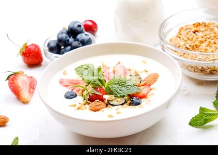 Possibilità di servire una ciotola alla granola con un mix di frutta secca, cereali, frutta e frutti di bosco, yogurt greco. Sana colazione vegetariana, fragola biologica, blueberr Foto Stock