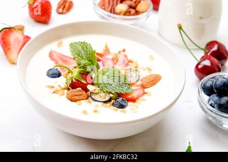 Possibilità di servire una ciotola alla granola con un mix di frutta secca, cereali, frutta e frutti di bosco, yogurt greco. Sana colazione vegetariana, fragola biologica, blueberr Foto Stock