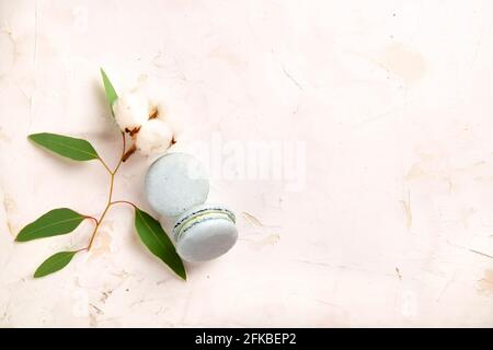 Elegante composizione di amaretti francesi eucalipto e bolo di cotone su tavola bianca in stucco testurizzata. Buon compleanno di San Valentino presente di primavera. Copia Foto Stock