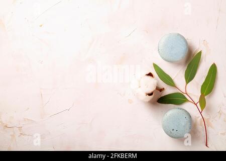 Elegante composizione di amaretti francesi eucalipto e bolo di cotone su tavola bianca in stucco testurizzata. Buon compleanno di San Valentino presente di primavera. Copia Foto Stock