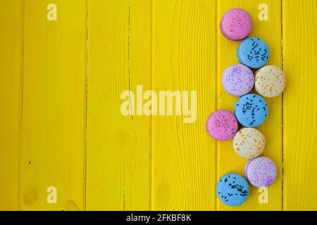 Dolci alla amarina francese, gusti e colori diversi. Macaron su sfondo giallo tavola di legno tessitura. Compleanno San Valentino presente. Copia testo sp Foto Stock