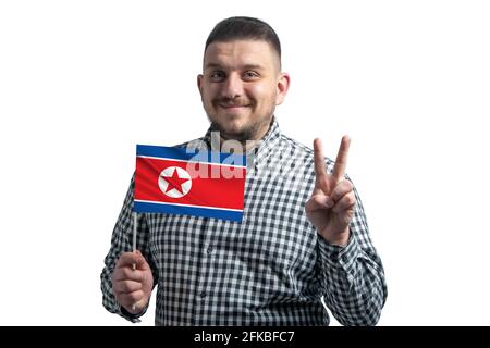 Ragazzo bianco che tiene una bandiera della Corea del Nord e mostra due dita isolate su uno sfondo bianco. Foto Stock