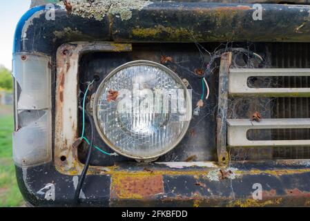 Una segnalazione di un faro e di una spia rotta di Un camion Dodge vecchio e arrugginito che è stato fuori nel tempo per molti anni Foto Stock