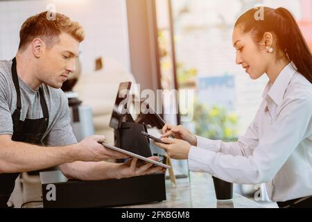 cafe cliente utilizzando mobile internet banking scansione QR codice di pagamento per caffè bevanda dal personale barista al banco, società senza contanti stile di vita moderno Foto Stock