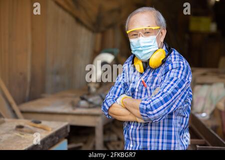 Ritratto di hobby di lavoro di legno anziano per il buon pensionamento, uomo asiatico maturo maestro professionale di legno artigianato mobili uomo produttore di legno. Foto Stock