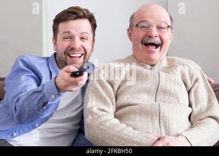 L'uomo anziano e il suo figlio maturo che si batte con la commedia ridendo di scherzi divertenti Foto Stock
