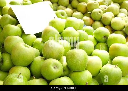 Un mazzo di mele granny smith biologiche croccanti, fresche, mature, etichetta prezzi in bianco al banco del mercato dei prodotti agricoli locali. Mangiare pulito concep Foto Stock