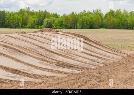 Livellamento di terreni e cantieri edili, preparazione per lavori edili, bulldozer o cingoli per escavatori su fondo sabbioso. Foto Stock