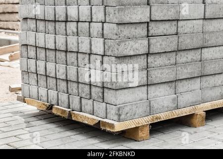 Una pila di lastre di pietra per pavimentazione impaccate di materiali per marciapiedi industriali su pallet in legno in un cantiere. Foto Stock