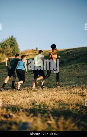 Vista posteriore di atleti maschili e femminili che corrono su erba terra Foto Stock