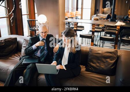 Imprenditore maschile e femminile che discute su computer portatile mentre si ha il caffè in caffetteria Foto Stock