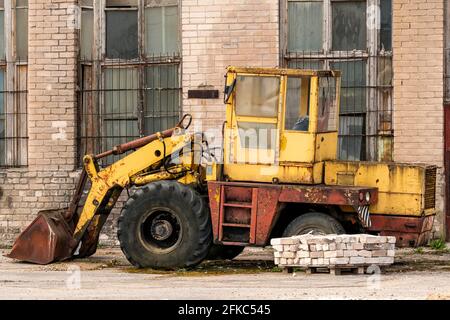 Vecchio bulldozer giallo rotto nel cortile di fabbrica abbandonato Foto Stock