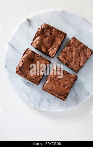 Vista dall'alto di quattro pezzi di brownie su un marmo platteria posta su una superficie bianca Foto Stock