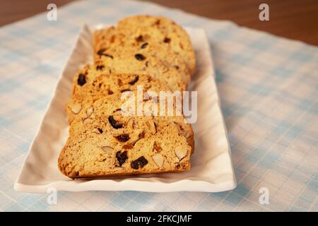 Biscotti alle mandorle appena sfornati su fondo in tessuto scacchi blu e bianco. Primo piano. Pausa pomeridiana. Foto Stock