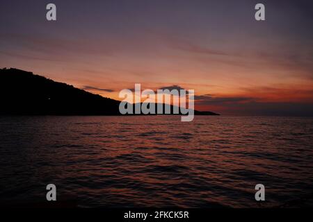 Una vista incredibile del tramonto da una barca. Silhouette di una costa dell'isola. Foto Stock