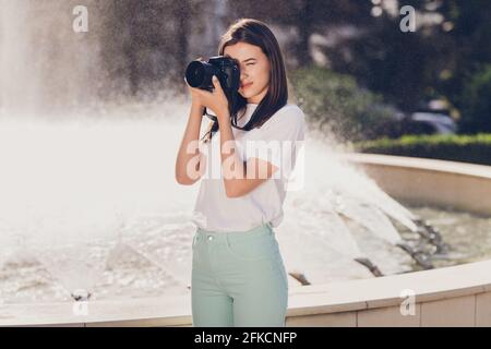 Ritratto di ragazza che scatta foto con la fotocamera che cattura la città viste a piedi vicino alla fontana Foto Stock