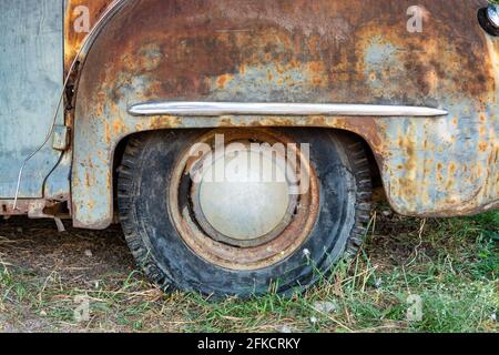 Ruota posteriore di un'auto americana arrugginita l'erba Foto Stock