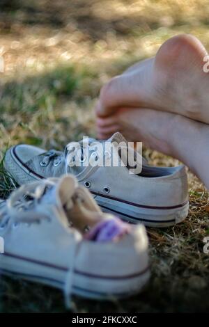 Parte dei piedi di una giovane donna e un paio di sneakers all'aperto nella natura in una giornata di sole in Francia Foto Stock