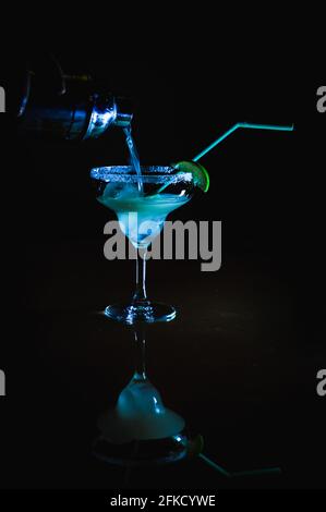 Cocktail ghiacciato con tequilla cointreau e succo di limone Versato dal cocktail shaker in un bicchiere di Margarita sale sul bordo e garni Foto Stock