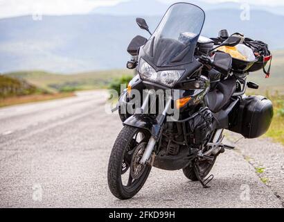 Una motocicletta parcheggiata sul lato di una strada Foto Stock