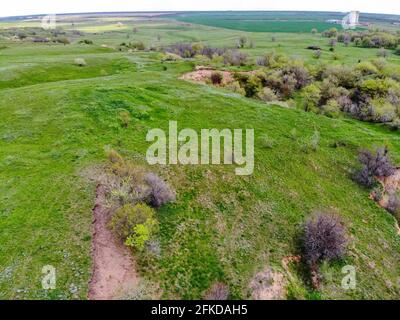 Verdi colline, campi e burroni visti dall'alto, naturale estate sfondo stagionale dal drone Foto Stock