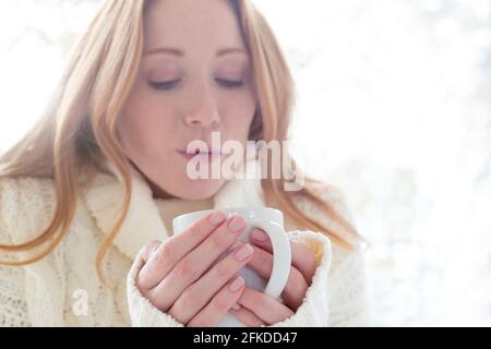 Donna che soffia su bevanda calda Foto Stock