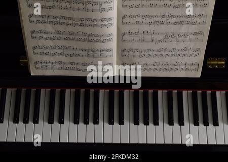 Scatto a testa di tasti del piano e un libro musicale su il rack musicale Foto Stock