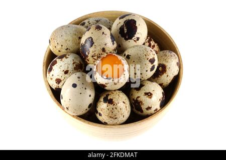 Una ciotola di legno piena di uova di quaglia fresche, una è aperta per mostrare il tuorlo Foto Stock