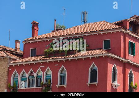 Tipico edificio veneziano. Pareti rosse con finestre gotiche bianche Foto Stock